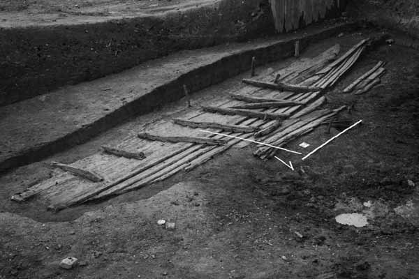 Drewniany wrak średniowiecznej łodzi klepkowej odkryty w warstwach ziemi podczas badań archeologicznych w Gdańsku przy ul. Wałowej 35.