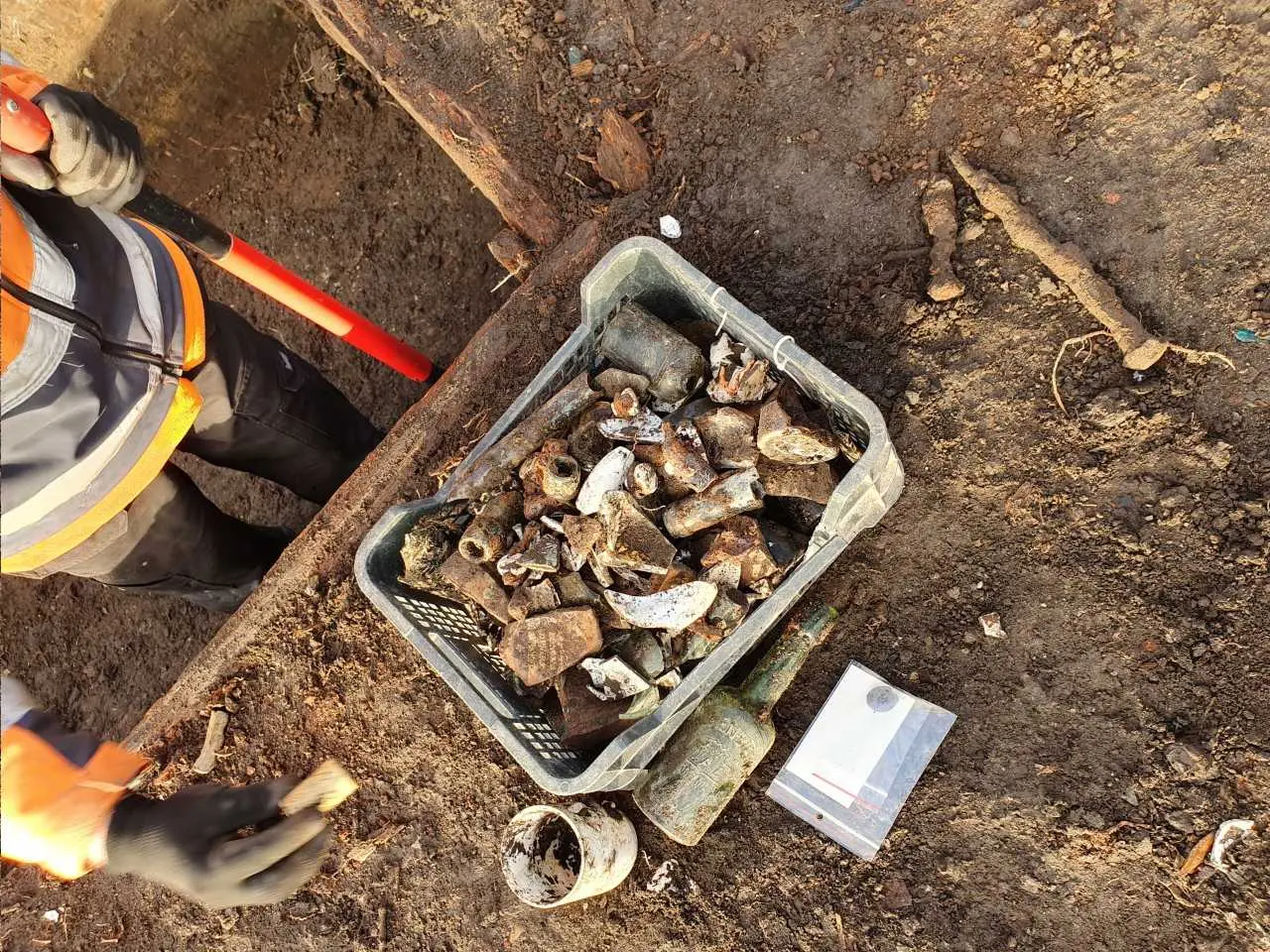 Inwentaryzacja zabytków ruchomych podczas nadzoru archeologicznego — ceramika, butelka szklana i obiekty metalowe zabezpieczone w terenie