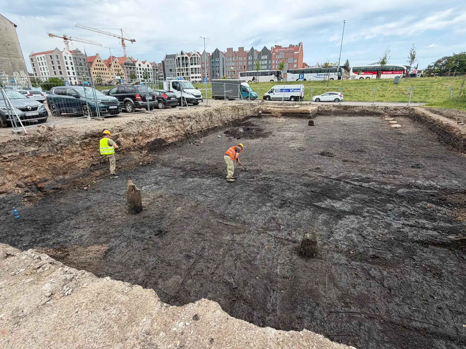 Wykop badawczy na Wyspie Spichrzów w Gdańsku, w tle historyczna zabudowa spichrzowa i dźwigi budowlane